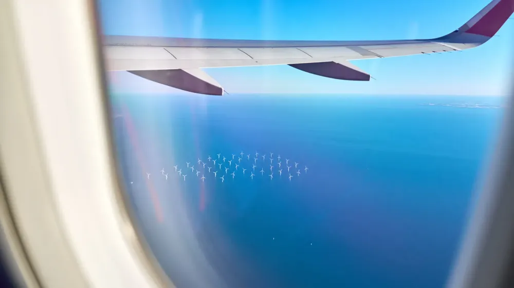 airplane flying over an ocean wind farm